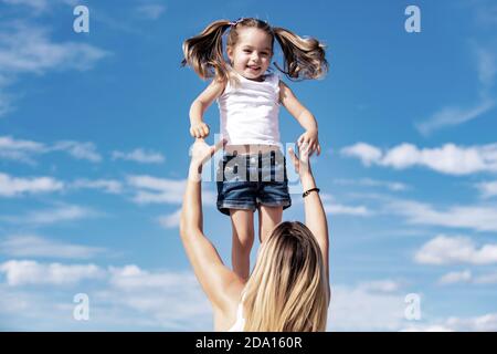 Ragazza eccitata. Felice famiglia d'amore - madre e figlia. Madre e figlia su sfondo blu cielo. Buon giorno delle madri. Foto Stock