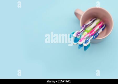 Primo piano di quattro spazzolini multicolore in un portabicchieri su sfondo blu con spazio per la copia, vista dall'alto. Il concetto di denti sani in Foto Stock