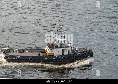 Rio de Janeiro, Brasile - 22 dicembre 2008: Primo piano di tugboat bianco-nero con equipaggio sul ponte nelle acque grigio scuro della baia di Guanabara. Foto Stock