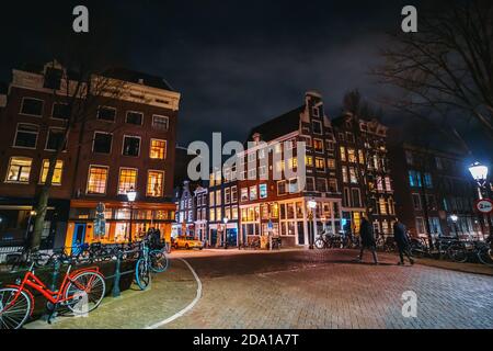 Amsterdam, Paesi Bassi - Marzo 2020: Vista notturna della città sul ponte sul canale d'acqua nel centro storico con tipiche case da ballo. Foto Stock