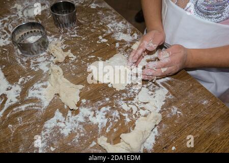 La bambina guarda le mani mentre gioca con pasta da pasticceria, figlia famiglia Foto Stock