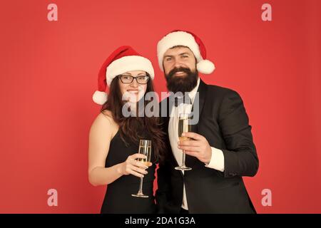 Festa di Natale. tuxedo uomo con la donna a santa hat. Buon Natale e saluti a tutti. business man e ragazza bere champagne. xmas party formali matura in amore festeggiare il nuovo anno. Foto Stock