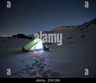 Tenda illuminata sulla neve ghiacciata sotto il cielo stellato nel Parco dell'Etna, Sicilia Foto Stock