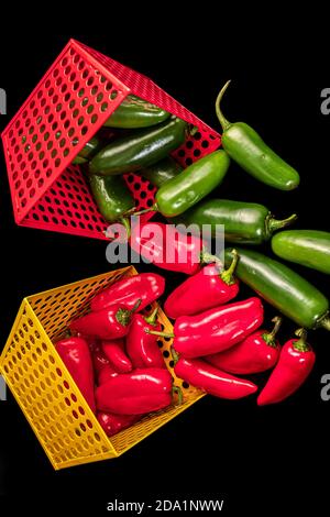 Peperoni rossi e verdi all'interno di cestelli metallici rossi e gialli Foto Stock