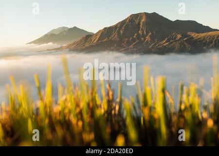 Vista all'alba del vulcano Batur a Bali dal villaggio di Pinggan. Bellissima alba e nuvole basse. Vista panoramica. Foto Stock