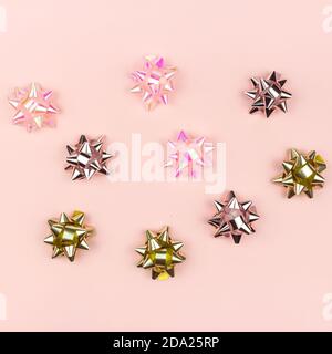 Composizione di Natale o Capodanno con fiocco dorato e brillante decorazione su sfondo rosa. Concetto creativo di Party Celebration. Foto Stock