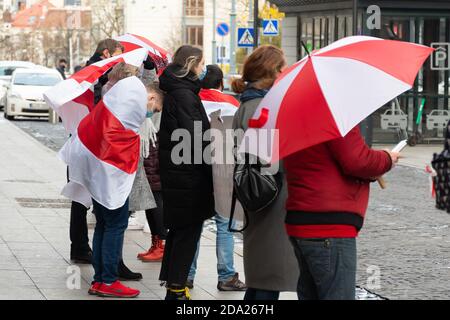 Protesta pacifica per sostenere la Bielorussia contro le repressioni e gli appelli in corso gratis con persone che indossano maschere e bandiere rosse e bianche Della Bielorussia Foto Stock