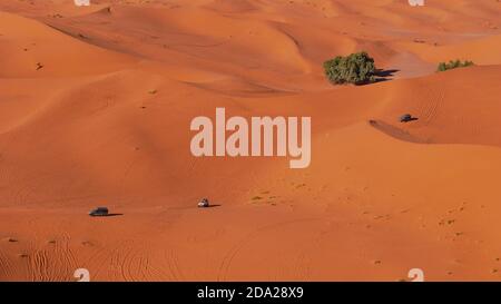 Merzouga, Marocco - 12/30/2019: Veduta aerea dei turisti che attraversano le famose dune di sabbia del deserto di Erg Chebbi con i loro veicoli fuoristrada. Foto Stock