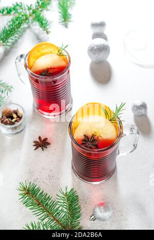 Vino rosso tritato natalizio con spezie, mele e arance su sfondo bianco. Bevanda calda tradizionale per le vacanze di Natale e d'inverno. Foto Stock