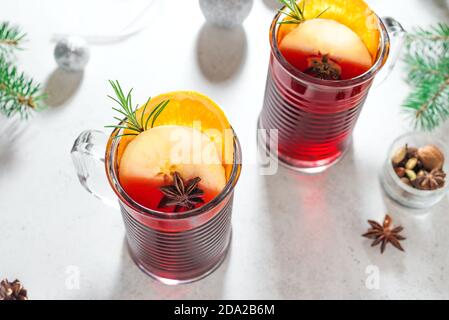 Vino rosso tritato natalizio con spezie, mele e arance su sfondo bianco. Bevanda calda tradizionale per le vacanze di Natale e d'inverno. Foto Stock