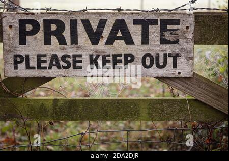 Un privato, si prega di tenere fuori segno su un cancello fattoria con filo spinato e ciottoli Foto Stock