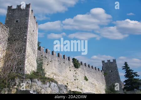 Il bordo della fortezza muraria di San Marino con torri. Il muro di pietra della fortezza sulla montagna. Foto Stock