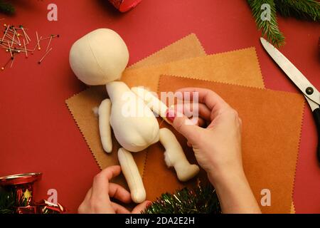 Creare bambola regalo di Natale per i bambini. Vista in primo piano di una bambola realizzata a mano con messa a fuoco selettiva degli accessori Foto Stock