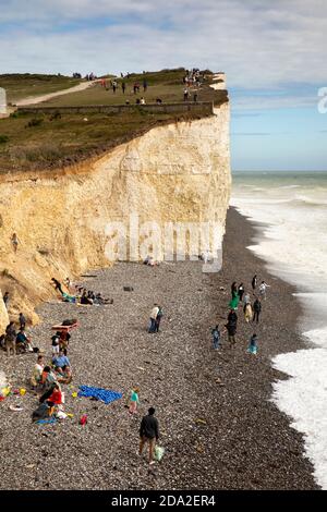 Regno Unito, Inghilterra, East Sussex, Birling Gap, visitatori sulla spiaggia di ghiaia sotto le scogliere di gesso che si innalzano a Beachy Head Foto Stock