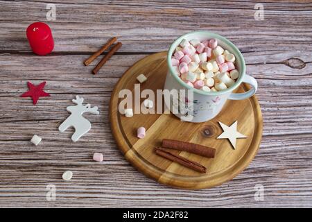 Concetto di Natale con marshmallows, cannella, forma a stella e candela su sfondo di legno Foto Stock