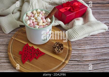 Concetto di Natale con pullover bianco, regalo, tazza di caffè, cannella su sfondo di legno Foto Stock