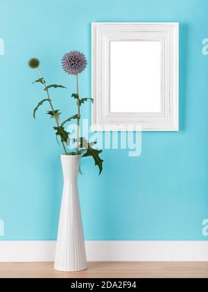 Mockup verticale con cornice bianca in shabby, modello con thistles globo in vaso davanti alla parete blu chiaro. Area immagine vuota mascherata con tracciato di ritaglio Foto Stock