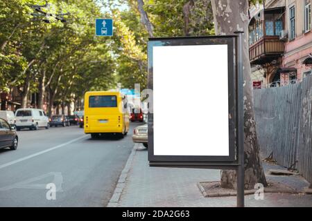 Blank mock up verticale strada cartellone in trafficata strada della città. L'autobus giallo viaggia su una linea dedicata in città Foto Stock