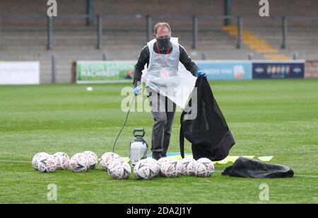 Un ufficiale che indossa DPI spruzzerà palloni con spray disinfettante prima del primo round della fa Cup Emirates tra Torquay United e Crawley Town a Plaimoor, Torquay. Foto James Boardman / Telephoto Images Foto Stock