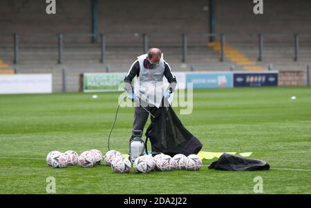 Un ufficiale che indossa DPI spruzzerà palloni con spray disinfettante prima del primo round della fa Cup Emirates tra Torquay United e Crawley Town a Plaimoor, Torquay. Foto James Boardman / Telephoto Images Foto Stock