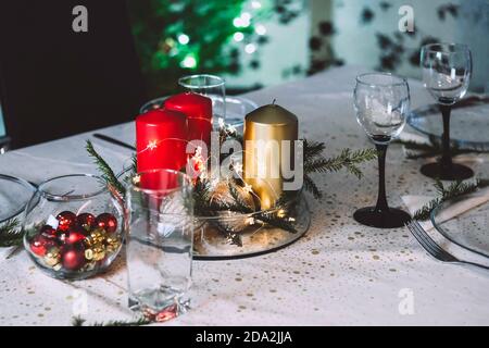 Bel tavolo di Natale con oro e candele rosse e bicchieri. Foto Stock