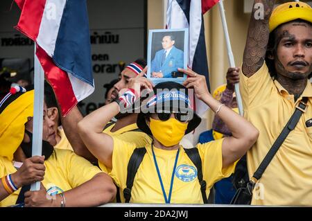 Una femmina tailandese sostenitrice royalist che indossa una maschera facciale tiene un ritratto di re Bhumibol (Rama IX) durante la dimostrazione. I sostenitori royalist thailandesi del re Maha Vajiralongkorn protestano chiedendo la protezione della monarchia mentre i manifestanti pro-democrazia si riuniscono al Monumento della democrazia. Foto Stock