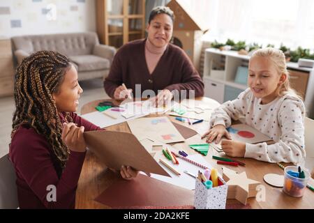 Ritratto di afroamericana ragazza che mostra foto mentre si gode arte e artigianato classe a scuola, copia spazio Foto Stock