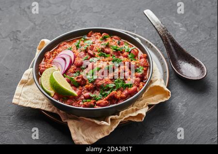 Rajma Masala Curry in ciotola nera su tavolo di ardesia scuro. Red Kidney Bean dal è un piatto vegetariano di cucina indiana. Cibo asiatico, pasto Foto Stock