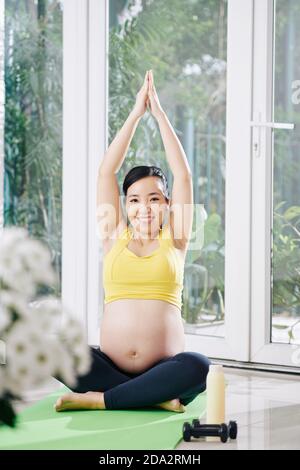 Donna incinta a praticare yoga Foto Stock