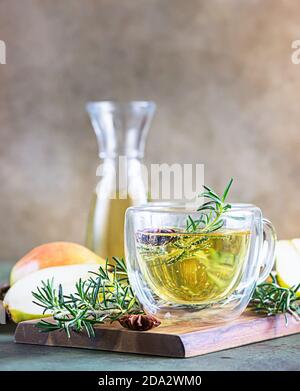 Tazze di vetro con pera calda o sidro di mela per Natale o Capodanno. Bevanda tradizionale autunnale o invernale con rosmarino, cannella e anice. Calcestruzzo verde Foto Stock