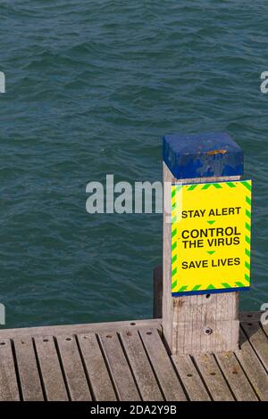 Resta vigile il controllo del virus salvare vite segno accanto al pontile sul molo Swanage a Swanage, Dorset UK nel mese di ottobre Foto Stock