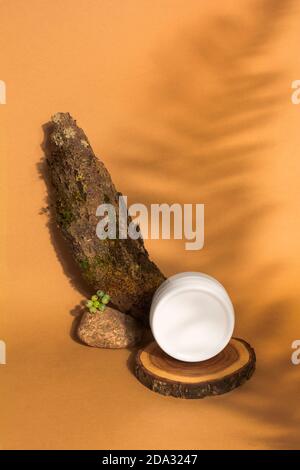 Crema naturale organica idratante in vasetto di plastica bianca sul podio in legno con decorazioni naturali e ombre. Look elegante del prodotto, simulato in su Foto Stock