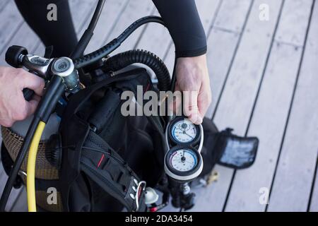 Subacqueo che si mette a punto e controlla il manometro, primo piano dell'attrezzatura per tenere la mano. Foto Stock