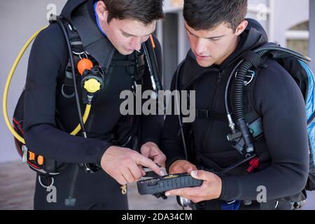 I subacquei che si mettono in moto e controllano i loro attrezzi, interagendo parlando del manometro Foto Stock