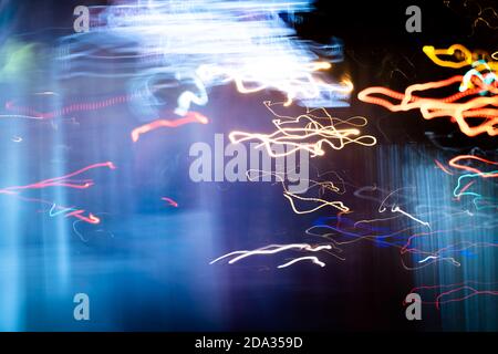 Foto di pittura con luce a lunga esposizione, linee curvy di colori vivaci al neon metallizzati giallo-arancio blu su sfondo nero. Foto Stock