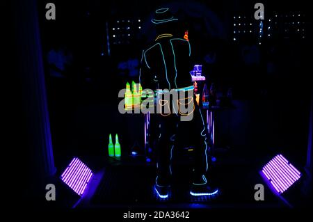 Barman professionista e spettacolo di luci a LED. Silhouette di moderno barman scuotendo drink al cocktail bar serale. Foto Stock