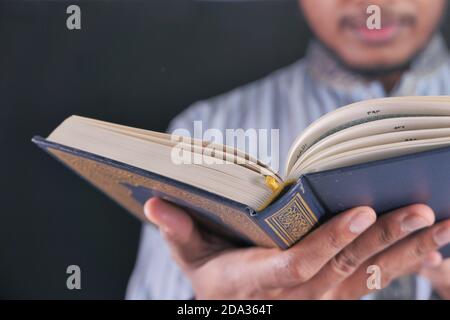La mano musulmana che legge quran di notte Foto Stock