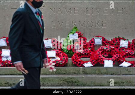 Southampton, Regno Unito, 8 novembre 2020. Ricordo Domenica 2020 input - Servizio di commemorazione tenuto al Cenotaph a Southampton, Regno Unito nella foto: Un uomo che indossa una maschera e che tiene croci adornati con papaveri passeggiate da wreaths papavero che sono stati messi alla base del Cenotaph a Southampton questa mattina, 8 novembre 2020. Un grande servizio pubblico si è svolto al Cenotaph di Southampton, Regno Unito, domenica 8 novembre 2020. La pandemia e il secondo blocco nazionale in Inghilterra hanno fatto sì che molti consigli locali abbiano dovuto modificare i piani di commemorazione quest'anno, incoraggiando i residenti a partecipare al saf Foto Stock