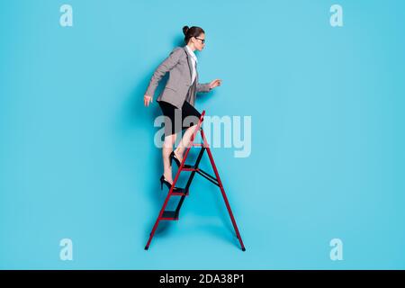 Foto laterale del profilo del corpo dell'ambiziosa scala di salita della signora carriera indossare gonna blazer isolato colore blu sfondo Foto Stock