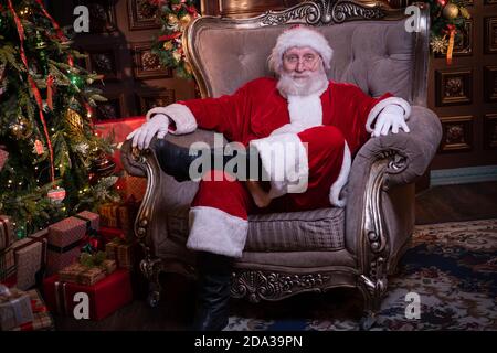 Ritratto Babbo Natale seduto in sedia vicino albero di Natale a. casa Foto Stock