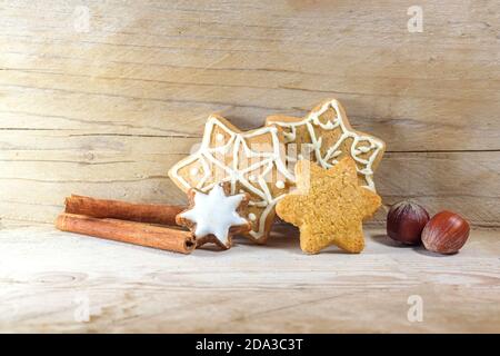 Biscotti di pan di zenzero a forma di stella, bastoncini di cannella e nocciole per Natale e Avvento, sfondo in legno rustico chiaro con spazio di copia, selezionato fo Foto Stock