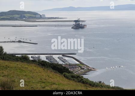 Hunterston Deep Water Harbor, North Ayrshire, Scozia, UK.Hunterston Terminal, nel North Ayrshire, La Scozia, era un porto per la movimentazione di minerali di ferro e carbone situato a Fairlie sul Firth di Clyde, gestito da Clydeport che è stato preso in consegna dal gruppo Peel nel 2003 in primo piano è Largs Marina con alcuni piccoli dingies vela lasciando il porto Foto Stock