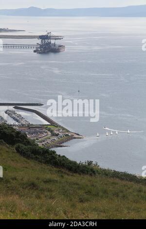 Hunterston Deep Water Harbor, North Ayrshire, Scozia, UK.Hunterston Terminal, nel North Ayrshire, La Scozia, era un porto per la movimentazione di minerali di ferro e carbone situato a Fairlie sul Firth di Clyde, gestito da Clydeport che è stato preso in consegna dal gruppo Peel nel 2003 in primo piano è Largs Marina con alcuni piccoli dingies vela lasciando il porto Foto Stock