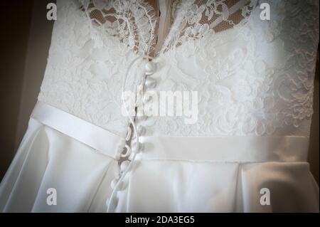 Primo piano sui dettagli dei pulsanti sul retro di un bellissimo abito da sposa bianco. Foto Stock