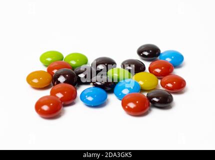 Le caramelle al cioccolato colorate sparse da vicino sembrano isolate su bianco sfondo Foto Stock