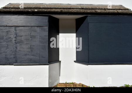 primo piano delle finestre della baia salite con la lavagna nera su una casa vuota dipinta di bianco alla luce del sole Foto Stock