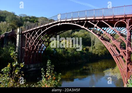 Splendido Ironbridge nello Shropshire che attraversa il fiume Servern in una giornata di sole con un cielo blu profondo. Il ponte è dipinto di rosso Foto Stock