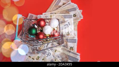 Il piccolo carrello di shopping pieno di palle dall'albero di Natale sta molto delle banconote. Foto Stock