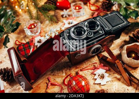 Fotocamera d'epoca con sfondo natalizio pieno di luci ancora vive su un tavolo di legno Foto Stock