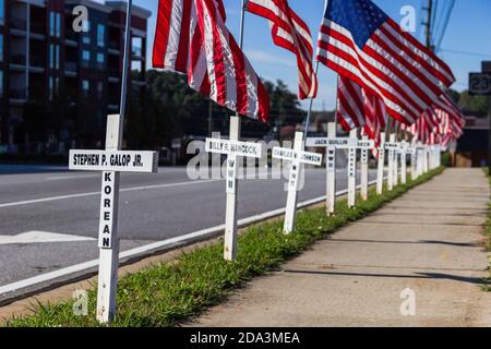 DULUTH, STATI UNITI - 07 novembre 2020: Duluth, Georgia / Stati Uniti - 6 novembre 2020: Croci bianche e bandiere americane fiancheggiano una strada cittadina in memor Foto Stock